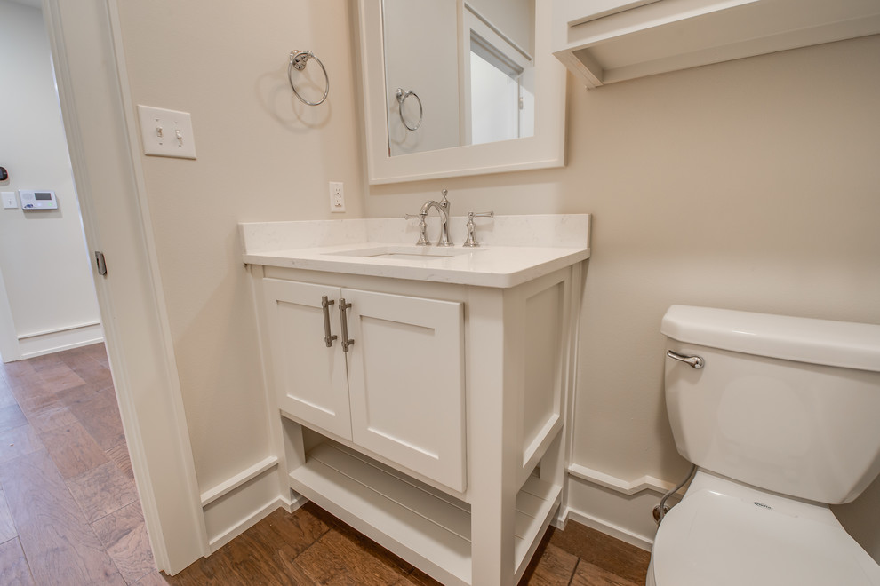 Idéer för att renovera ett litet funkis vit vitt badrum med dusch, med skåp i shakerstil, vita skåp, en toalettstol med separat cisternkåpa, beige väggar, mellanmörkt trägolv, ett undermonterad handfat, bänkskiva i kvarts och brunt golv