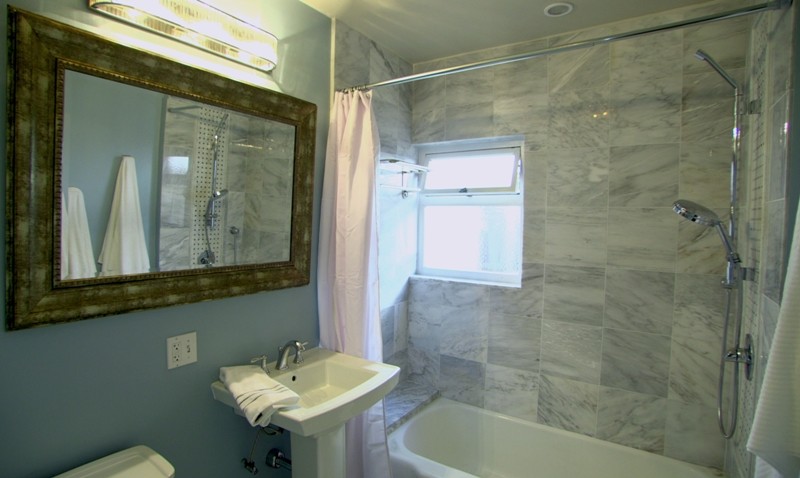 Immagine di una stanza da bagno chic con lavabo a colonna, vasca ad alcova, vasca/doccia, WC monopezzo, piastrelle grigie e piastrelle in pietra