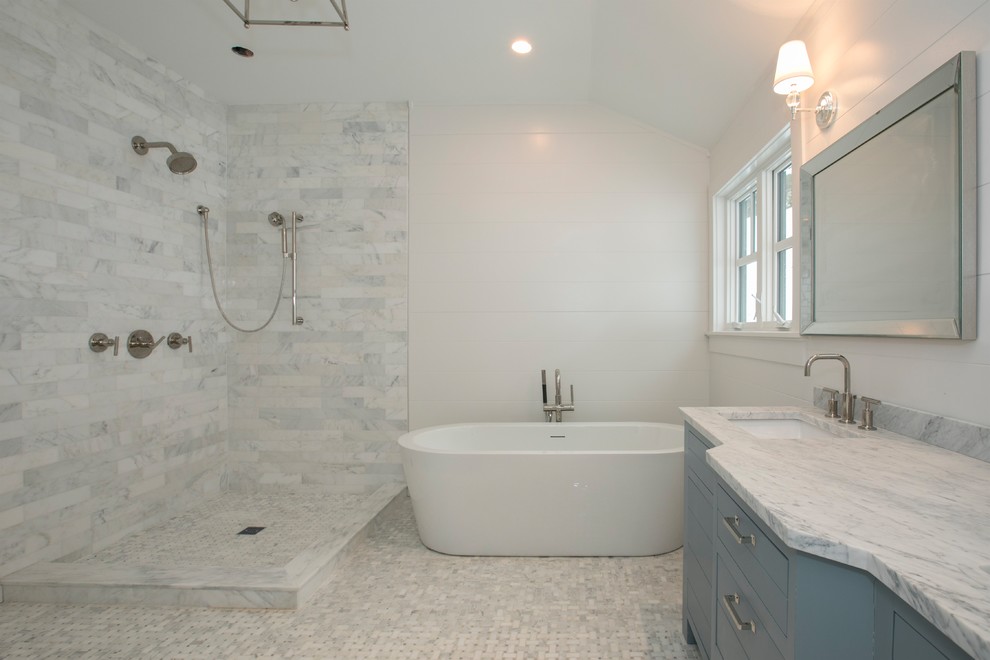 This is an example of a medium sized farmhouse ensuite bathroom in New York with flat-panel cabinets, blue cabinets, a freestanding bath, a corner shower, a two-piece toilet, white tiles, marble tiles, white walls, marble flooring, a submerged sink, marble worktops, white floors, an open shower and white worktops.