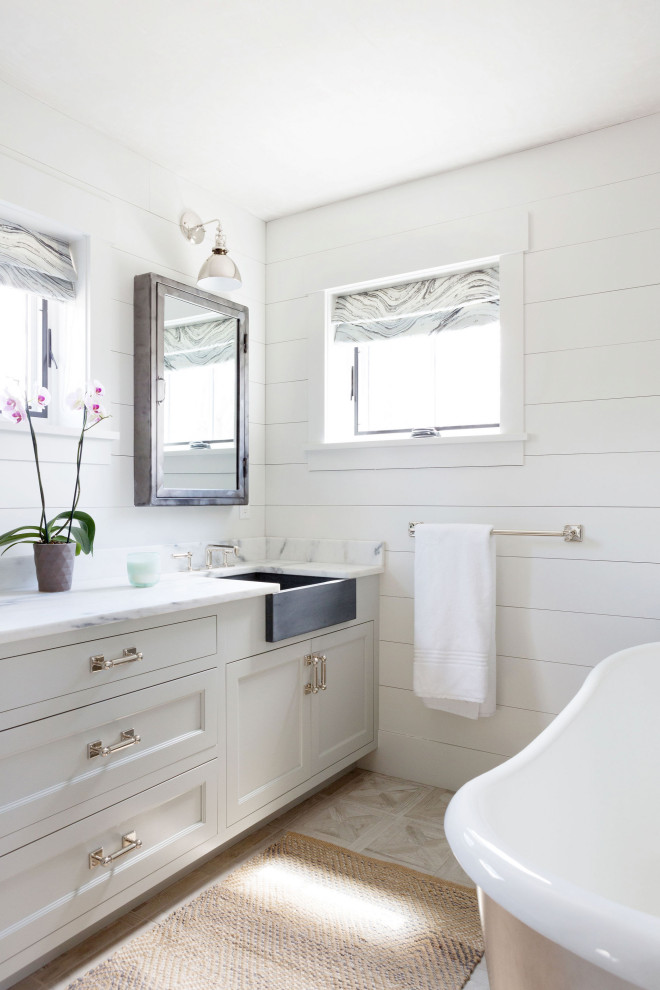 Idée de décoration pour une salle de bain principale champêtre de taille moyenne avec un placard à porte shaker, des portes de placard grises, une baignoire indépendante, un mur blanc, un lavabo encastré, un sol beige, un plan de toilette blanc, meuble simple vasque, meuble-lavabo encastré et du lambris de bois.