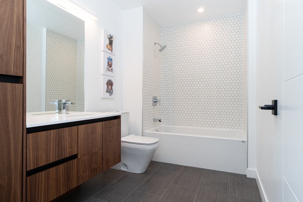 Idéer för funkis vitt badrum med dusch, med släta luckor, skåp i mörkt trä, ett badkar i en alkov, en dusch/badkar-kombination, en toalettstol med hel cisternkåpa, vit kakel, mosaik, vita väggar, ett undermonterad handfat och grått golv