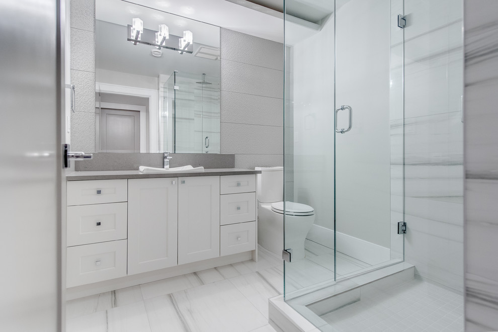 Medium sized contemporary shower room bathroom in Vancouver with recessed-panel cabinets, white cabinets, engineered stone worktops, a two-piece toilet, grey tiles, porcelain tiles, a corner shower, grey walls and a built-in sink.