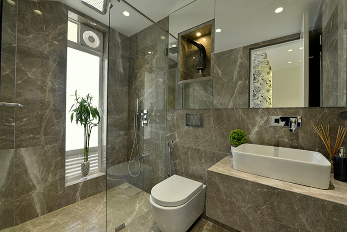 This is an example of a small contemporary bathroom in Mumbai with flat-panel cabinets, a wall mounted toilet, marble flooring, a console sink and marble worktops.
