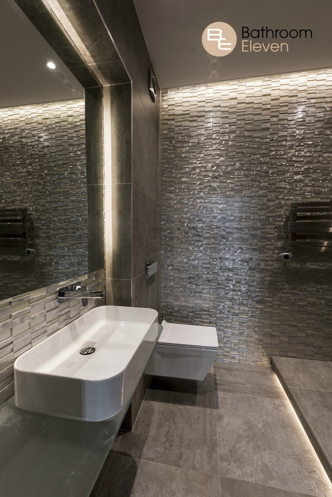 На фото: детская ванная комната в современном стиле с открытым душем, инсталляцией, коричневой плиткой, плиткой мозаикой, коричневыми стенами, полом из цементной плитки, раковиной с несколькими смесителями и стеклянной столешницей