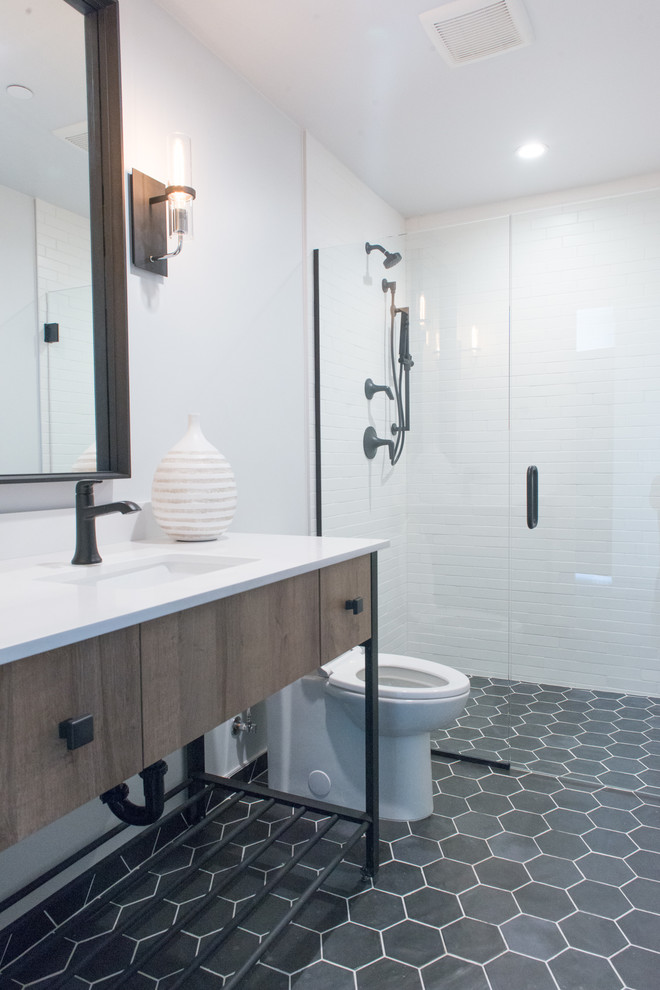 Mid-sized urban white tile and ceramic tile ceramic tile and black floor walk-in shower photo in Phoenix with flat-panel cabinets, brown cabinets, a one-piece toilet, white walls, an undermount sink, quartzite countertops, a hinged shower door and white countertops