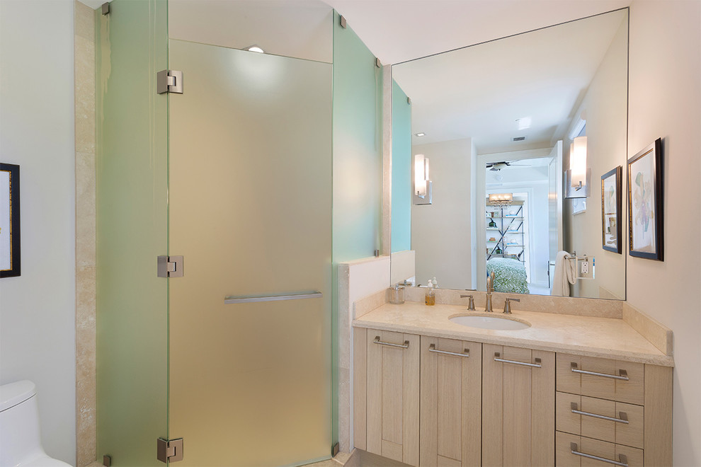 Свежая идея для дизайна: главная ванная комната среднего размера в морском стиле с плоскими фасадами, светлыми деревянными фасадами, ванной в нише, душем в нише, унитазом-моноблоком, бежевыми стенами, полом из керамогранита, врезной раковиной, мраморной столешницей, бежевым полом, душем с распашными дверями и бежевой столешницей - отличное фото интерьера