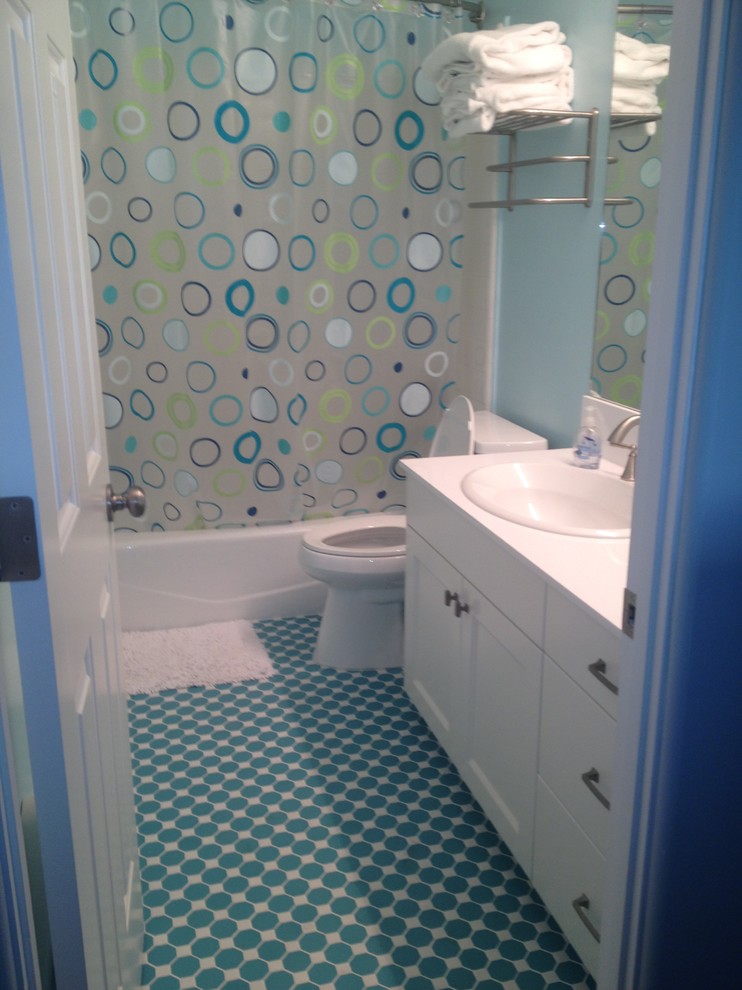 Réalisation d'une petite salle d'eau design avec un placard à porte shaker, des portes de placard blanches, une baignoire en alcôve, un combiné douche/baignoire, WC séparés, un mur bleu, un sol en vinyl, un lavabo posé, un plan de toilette en surface solide, un sol bleu et une cabine de douche avec un rideau.