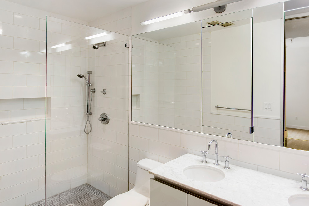 Foto di una stanza da bagno industriale con ante di vetro, top in marmo, doccia aperta, piastrelle grigie e pareti gialle