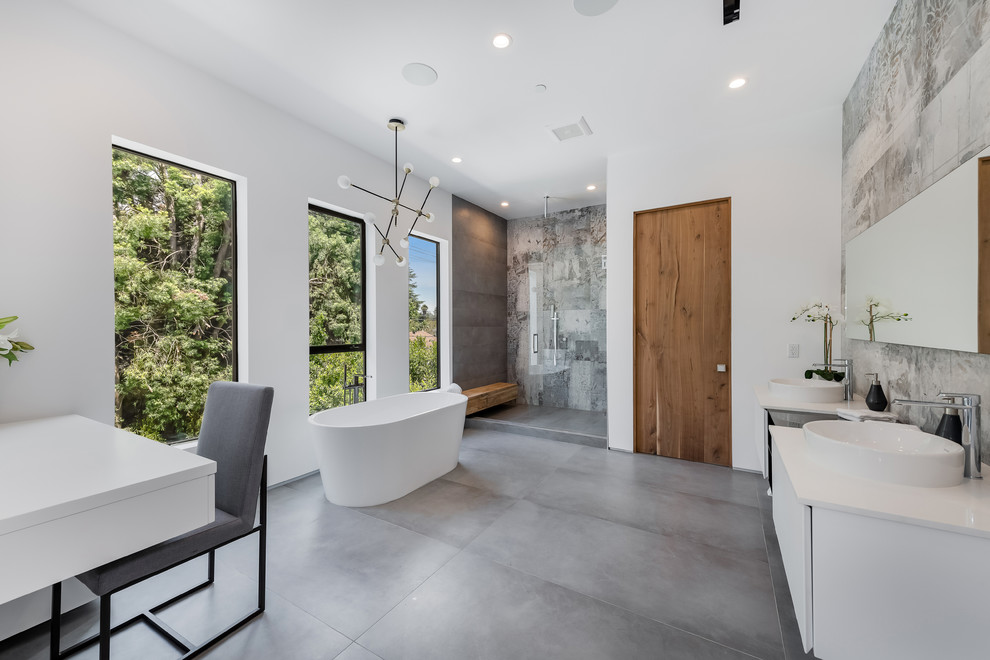 Пример оригинального дизайна: главная ванная комната в современном стиле с плоскими фасадами, белыми фасадами, отдельно стоящей ванной, душем в нише, серой плиткой, настольной раковиной, серым полом и белой столешницей