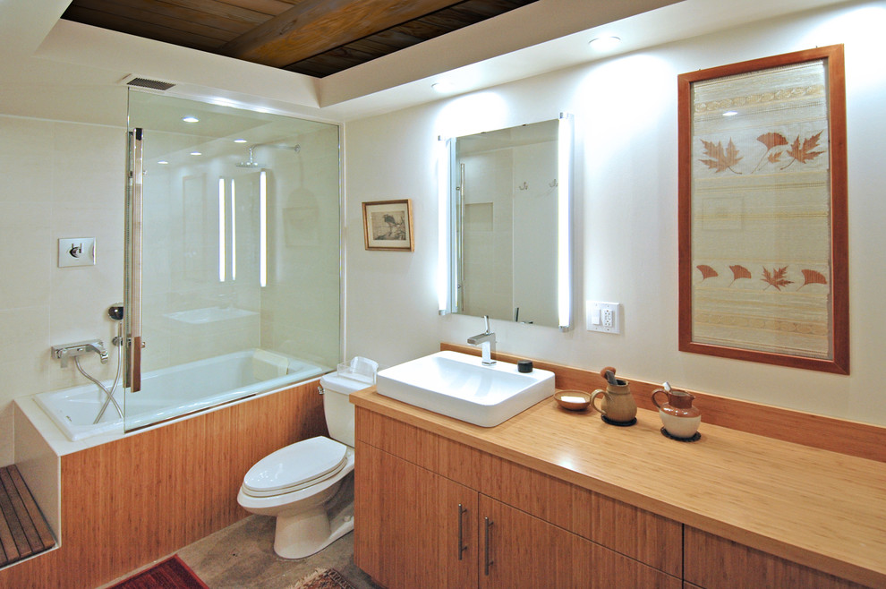 Exemple d'une salle de bain principale tendance en bois clair de taille moyenne avec une vasque, un placard à porte plane, un plan de toilette en bois, un bain japonais, un combiné douche/baignoire, WC séparés, un carrelage beige, un carrelage de pierre, un mur blanc et sol en béton ciré.