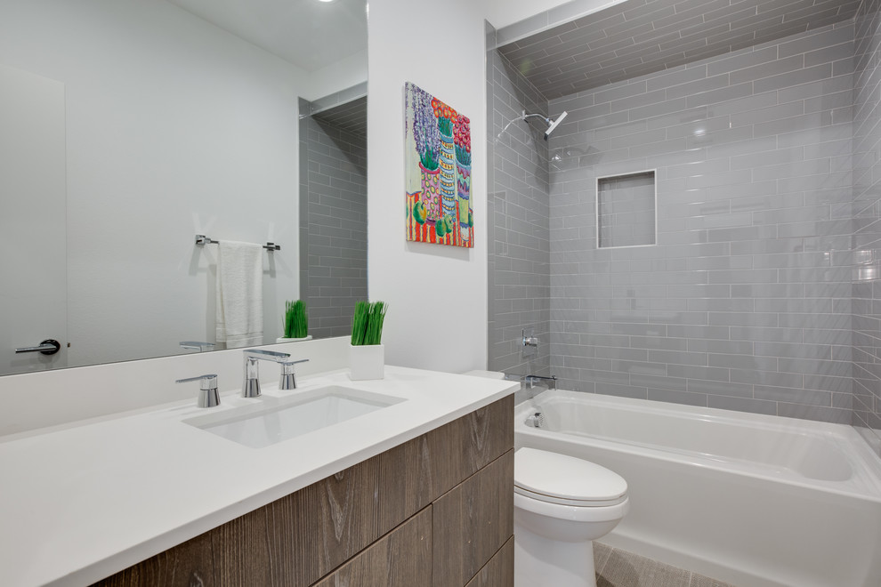 Пример оригинального дизайна: ванная комната среднего размера в стиле модернизм с плоскими фасадами, темными деревянными фасадами, ванной в нише, душем над ванной, раздельным унитазом, серой плиткой, плиткой кабанчик, белыми стенами, полом из ламината, душевой кабиной, врезной раковиной, столешницей из искусственного камня, бежевым полом, шторкой для ванной и белой столешницей