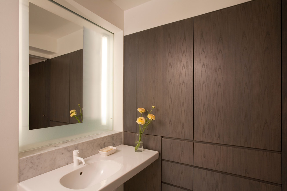Modernes Badezimmer mit integriertem Waschbecken, flächenbündigen Schrankfronten und dunklen Holzschränken in New York