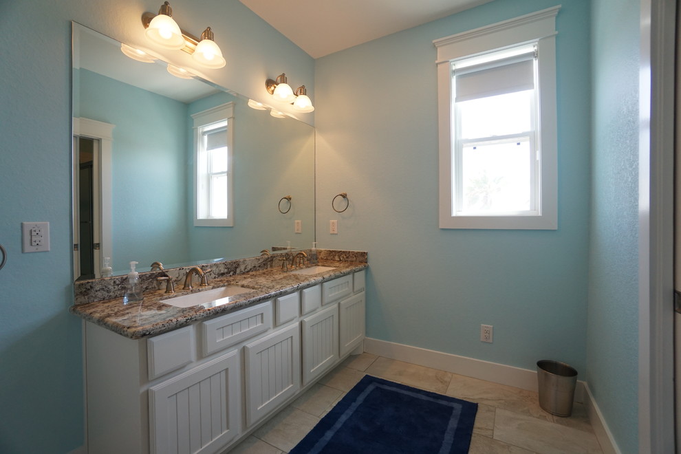Идея дизайна: главная ванная комната среднего размера в морском стиле с врезной раковиной, фасадами с декоративным кантом, белыми фасадами, столешницей из гранита, бежевой плиткой, керамической плиткой, синими стенами, полом из керамической плитки и угловым душем