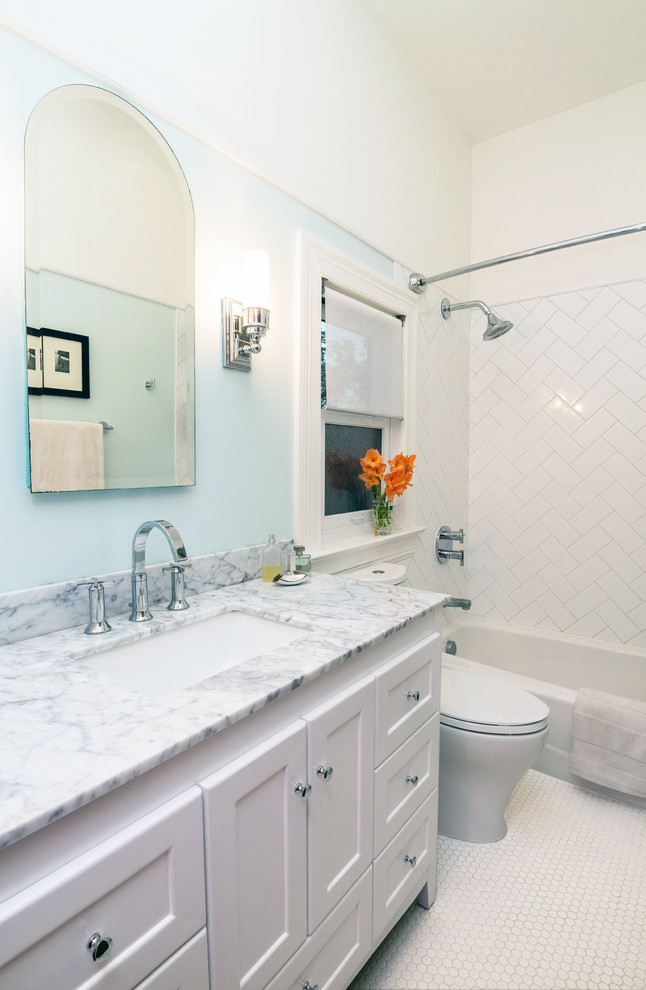 Diseño de cuarto de baño clásico con bañera empotrada, combinación de ducha y bañera, paredes azules, suelo con mosaicos de baldosas, lavabo bajoencimera, baldosas y/o azulejos blancos y ventanas