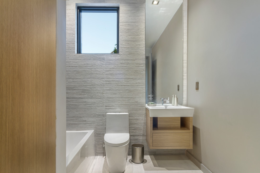 Photo of a contemporary shower room bathroom in Miami with flat-panel cabinets, light wood cabinets, an alcove bath, grey tiles, grey walls, a console sink and grey floors.