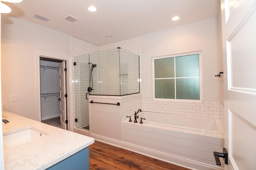 Bathroom - large craftsman master white tile and subway tile vinyl floor and brown floor bathroom idea in Other with shaker cabinets, blue cabinets, a two-piece toilet, white walls, an undermount sink, quartz countertops, a hinged shower door and white countertops