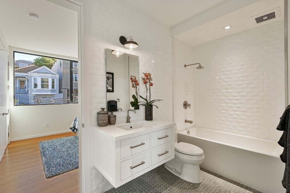 Exempel på ett modernt vit vitt badrum, med släta luckor, vita skåp, ett badkar i en alkov, en dusch/badkar-kombination, vit kakel, ett undermonterad handfat, grått golv och med dusch som är öppen