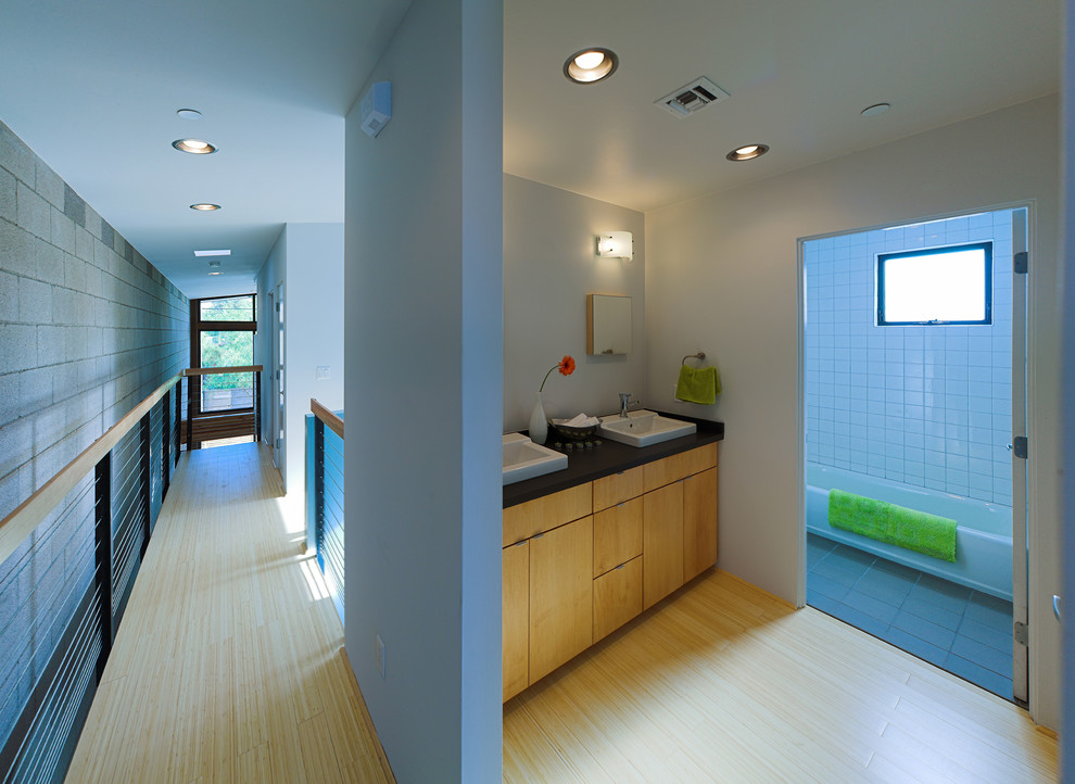 Inspiration pour une petite salle de bain minimaliste en bois clair avec un placard à porte plane, un plan de toilette en stratifié, une baignoire en alcôve, un combiné douche/baignoire, un carrelage blanc, des carreaux de céramique, un mur gris et parquet en bambou.