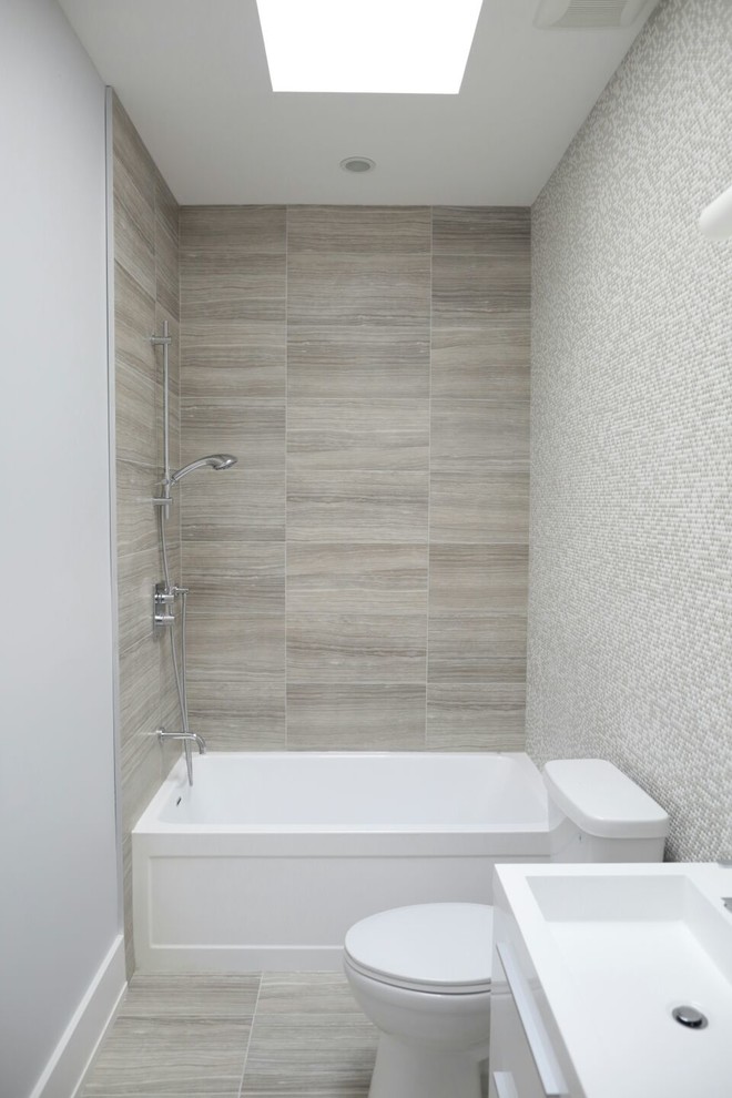 На фото: маленькая главная ванная комната в современном стиле с плоскими фасадами, белыми фасадами, ванной в нише, душем в нише, раздельным унитазом, бежевой плиткой, белой плиткой, плиткой мозаикой, серыми стенами, полом из керамогранита и монолитной раковиной для на участке и в саду