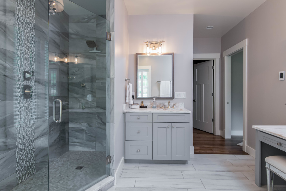 Inspiration for a mid-sized craftsman master gray tile and stone tile ceramic tile and white floor bathroom remodel in Other with shaker cabinets, gray cabinets, a one-piece toilet, gray walls, an undermount sink, marble countertops, a hinged shower door and white countertops