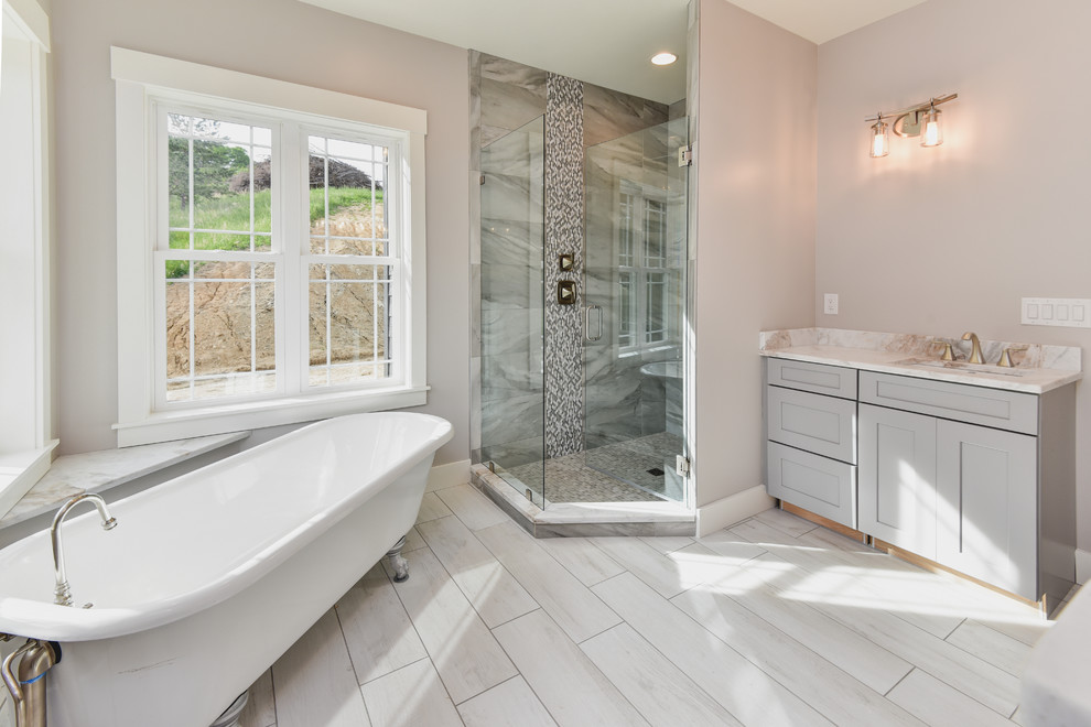 Bathroom - mid-sized craftsman master gray tile and stone tile ceramic tile and white floor bathroom idea in Other with shaker cabinets, gray cabinets, a one-piece toilet, gray walls, an undermount sink, marble countertops, a hinged shower door and white countertops