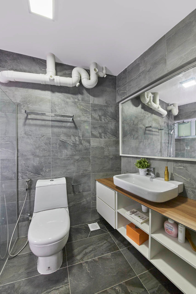 Exemple d'une petite salle de bain principale scandinave avec un placard sans porte, des portes de placard blanches, une douche ouverte, WC à poser, un carrelage gris, des carreaux de céramique, un mur gris, un sol en ardoise, un lavabo posé et un plan de toilette en bois.