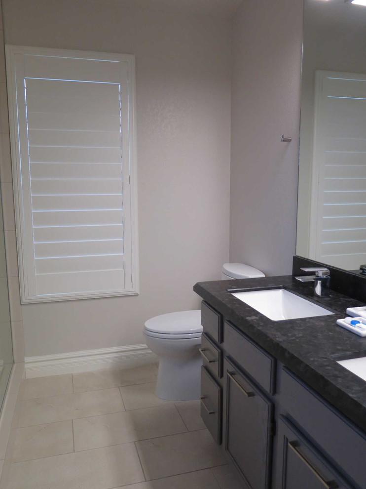 This is an example of a small contemporary ensuite bathroom in Phoenix with raised-panel cabinets, grey cabinets, a walk-in shower, a one-piece toilet, beige tiles, porcelain tiles, beige walls, porcelain flooring, a submerged sink and granite worktops.
