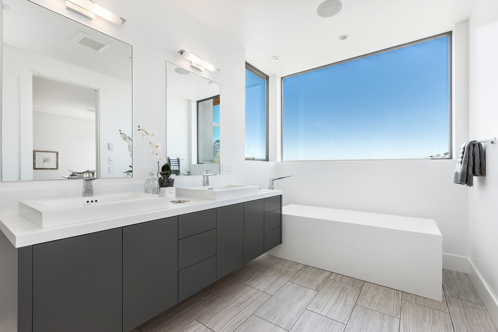 Modelo de cuarto de baño actual con armarios con paneles lisos, puertas de armario grises, paredes blancas, lavabo encastrado y encimeras blancas