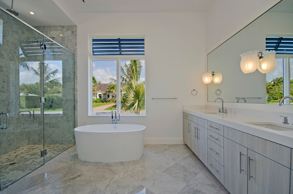 Exemple d'une douche en alcôve tendance avec un lavabo encastré, un placard à porte plane, des portes de placard grises, une baignoire indépendante, un carrelage gris et un plan de toilette blanc.