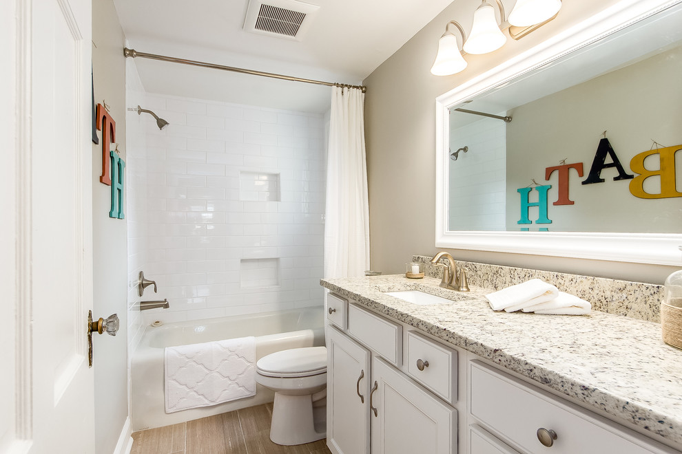 Bathroom - small traditional white tile and ceramic tile ceramic tile bathroom idea in Columbus with an undermount sink, recessed-panel cabinets, white cabinets, granite countertops, a one-piece toilet and beige walls