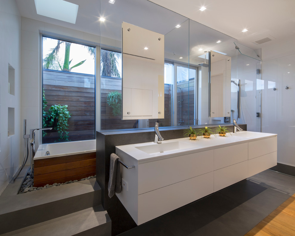 На фото: главная ванная комната в современном стиле с плоскими фасадами, белыми фасадами, отдельно стоящей ванной, открытым душем, белой плиткой, белыми стенами, монолитной раковиной, серым полом и душем с распашными дверями