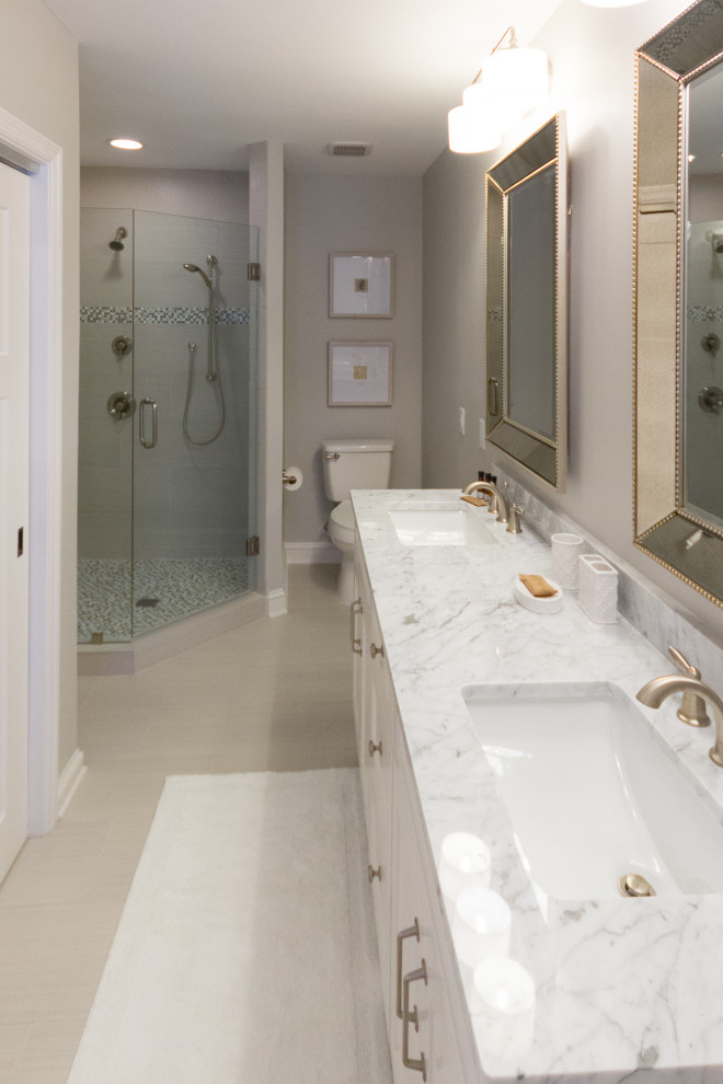 Inspiration for a medium sized coastal ensuite bathroom in Atlanta with shaker cabinets, white cabinets, a corner shower, a two-piece toilet, white tiles, porcelain tiles, grey walls, porcelain flooring, a submerged sink, marble worktops, grey floors, a hinged door, white worktops, double sinks and a floating vanity unit.