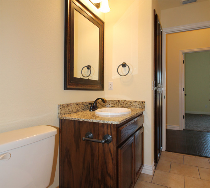 Modelo de cuarto de baño principal tradicional grande con armarios con paneles empotrados, puertas de armario marrones, paredes beige, lavabo encastrado, encimera de granito y suelo beige