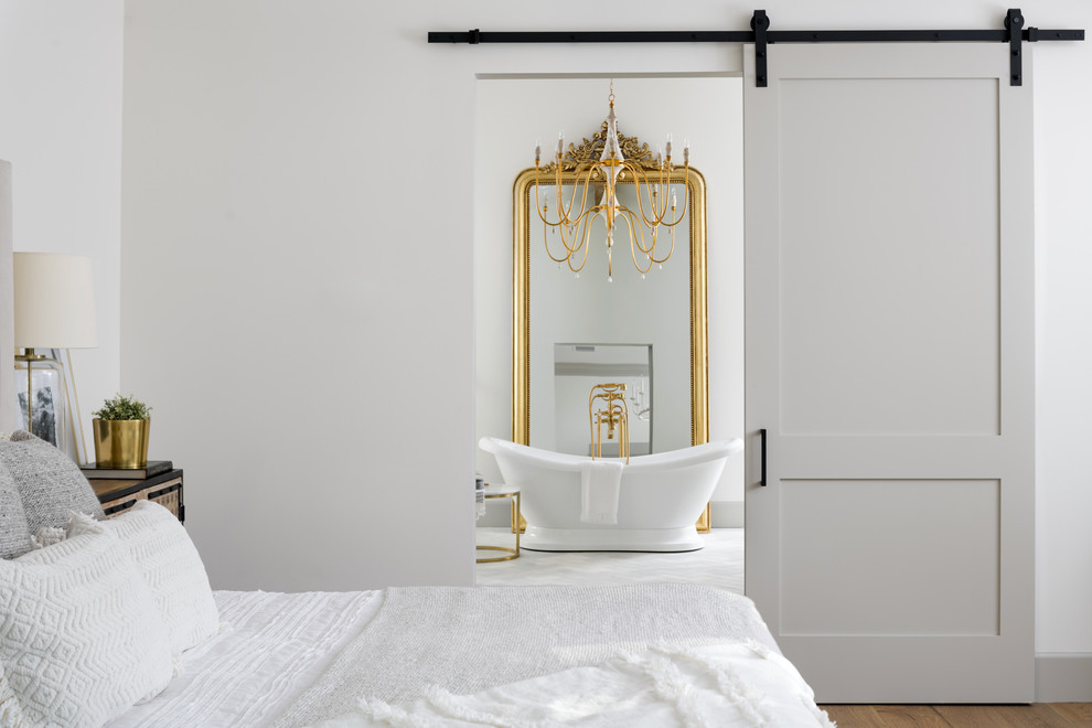 Immagine di una grande stanza da bagno padronale country con vasca con piedi a zampa di leone, parquet chiaro, lavabo sottopiano, top in marmo e top bianco