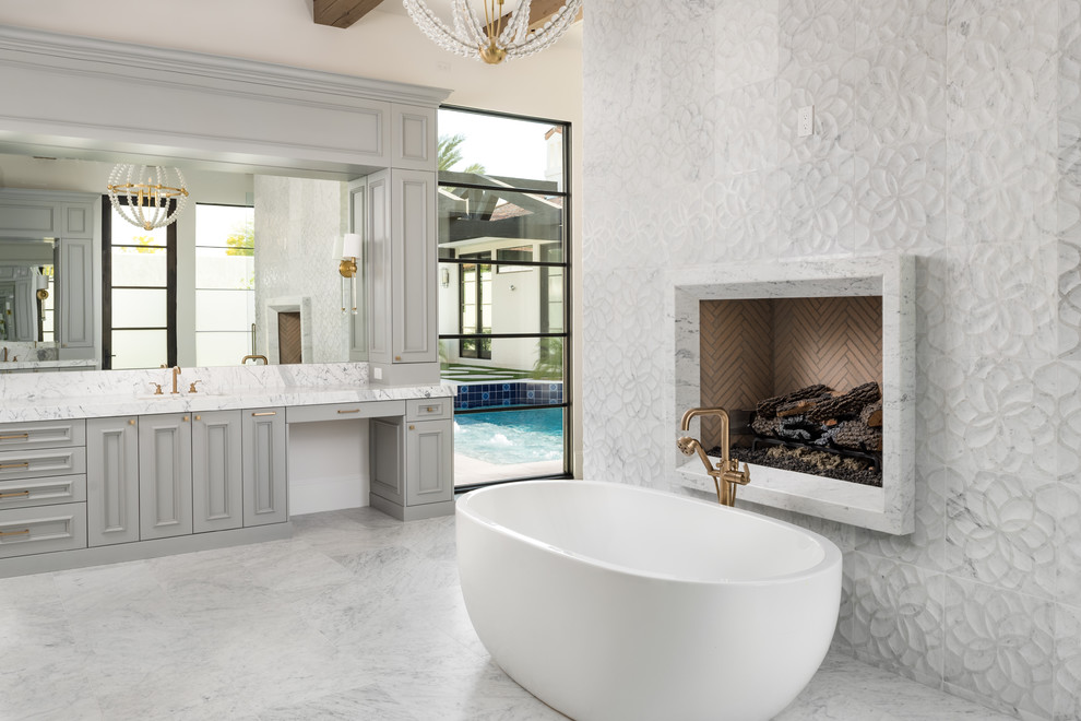 Photo of a traditional bathroom in Phoenix with recessed-panel cabinets, grey cabinets, a freestanding bath, beige walls, grey floors and white worktops.