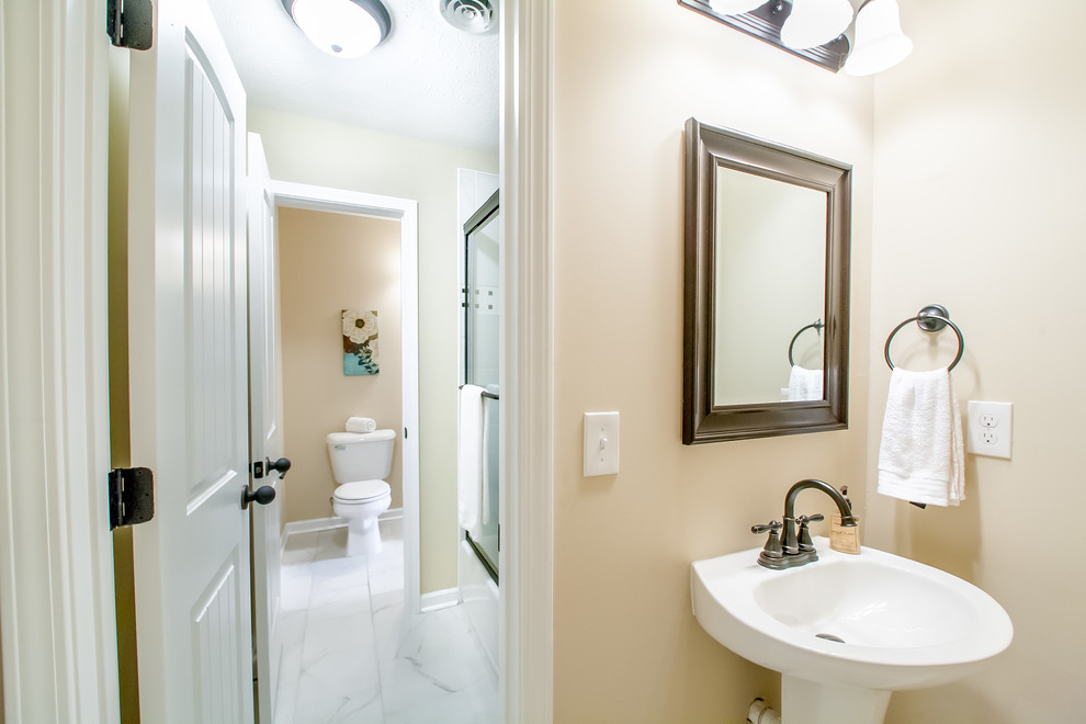 This is an example of a medium sized classic shower room bathroom in Nashville with a pedestal sink, raised-panel cabinets, a shower/bath combination, a two-piece toilet, white tiles, ceramic tiles, beige walls and ceramic flooring.