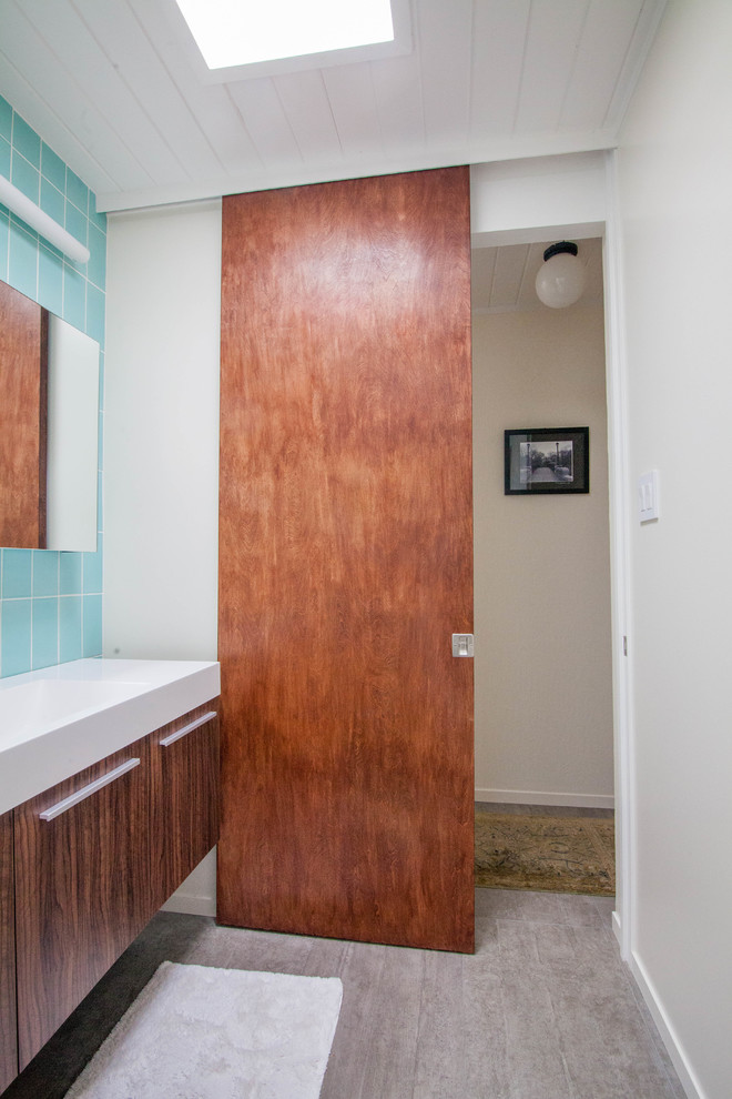 Ispirazione per una stanza da bagno minimalista di medie dimensioni con ante in legno bruno, vasca ad angolo, vasca/doccia, piastrelle blu, piastrelle in ceramica, pareti bianche e porta doccia a battente