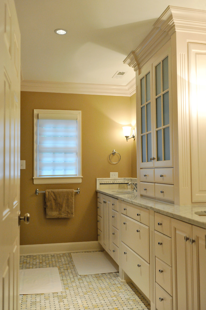 シャーロットにある中くらいなトラディショナルスタイルのおしゃれなマスターバスルーム (黄色い壁、レイズドパネル扉のキャビネット、白いキャビネット、白いタイル、セラミックタイルの床、アンダーカウンター洗面器、大理石の洗面台) の写真