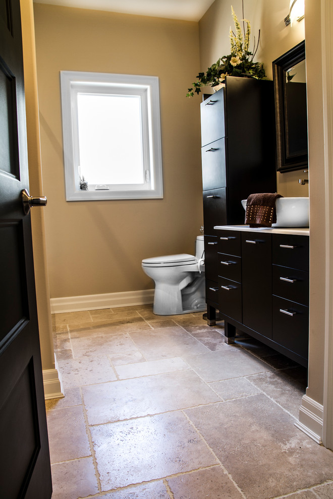 Idées déco pour une salle de bain classique en bois foncé de taille moyenne pour enfant avec un placard à porte plane, WC à poser, un carrelage beige, un carrelage de pierre, un mur marron, une vasque et un plan de toilette en surface solide.