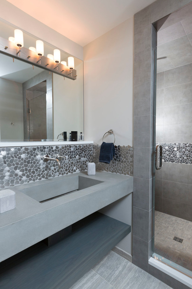 Foto på ett stort funkis grå en-suite badrum, med grå kakel, kakel i småsten, grå väggar, klinkergolv i porslin, öppna hyllor, en dusch i en alkov, ett integrerad handfat, bänkskiva i betong, grått golv och dusch med gångjärnsdörr