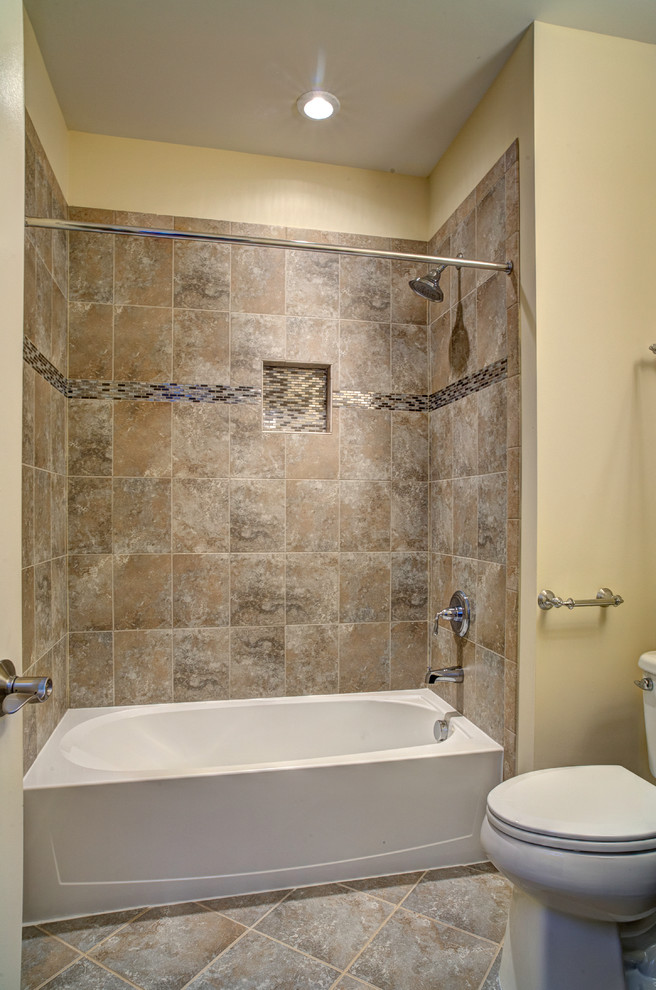 Immagine di una grande stanza da bagno american style con vasca ad alcova, vasca/doccia, piastrelle beige, pareti beige, pavimento marrone, doccia con tenda e WC a due pezzi