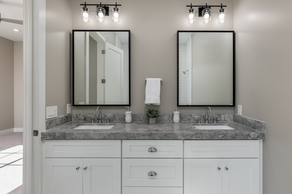 Réalisation d'une salle de bain tradition avec un placard à porte shaker, des portes de placard blanches, un mur gris, un lavabo encastré et un plan de toilette gris.