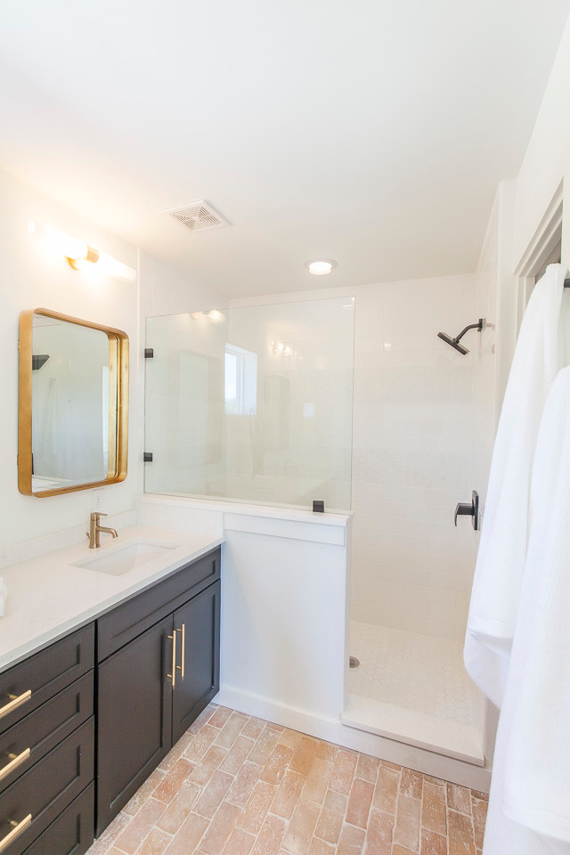 Cette photo montre une douche en alcôve principale tendance de taille moyenne avec un placard à porte shaker, des portes de placard noires, un mur blanc, un sol en brique et un lavabo encastré.