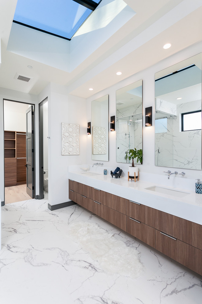 Modelo de cuarto de baño principal contemporáneo con armarios con paneles lisos, puertas de armario de madera en tonos medios, paredes blancas, lavabo bajoencimera, suelo blanco, encimeras blancas y espejo con luz