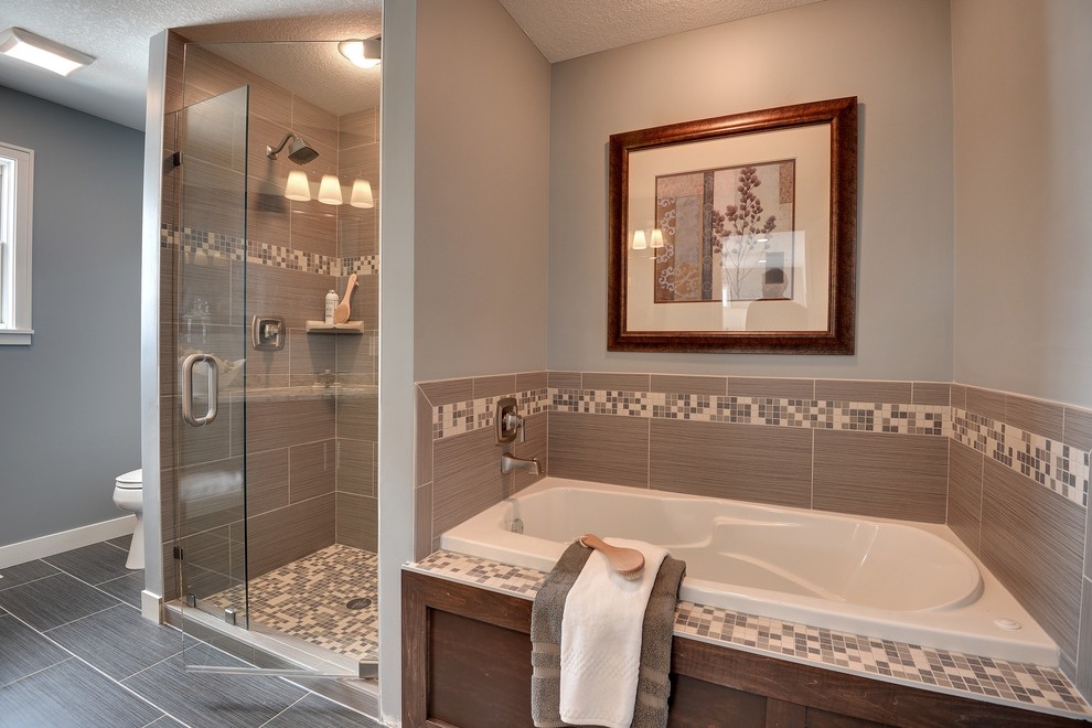 Immagine di una stanza da bagno tradizionale con vasca da incasso, doccia alcova e piastrelle grigie