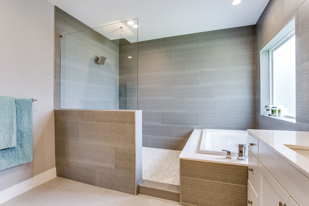 Exempel på ett stort modernt vit vitt en-suite badrum, med släta luckor, vita skåp, ett hörnbadkar, en dusch/badkar-kombination, en toalettstol med separat cisternkåpa, grå kakel, porslinskakel, grå väggar, klinkergolv i porslin, ett undermonterad handfat, marmorbänkskiva, grått golv och med dusch som är öppen