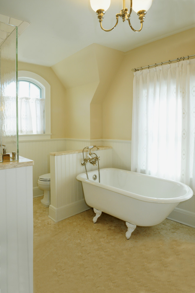 На фото: ванная комната с ванной на ножках, душем в нише и каменной плиткой с