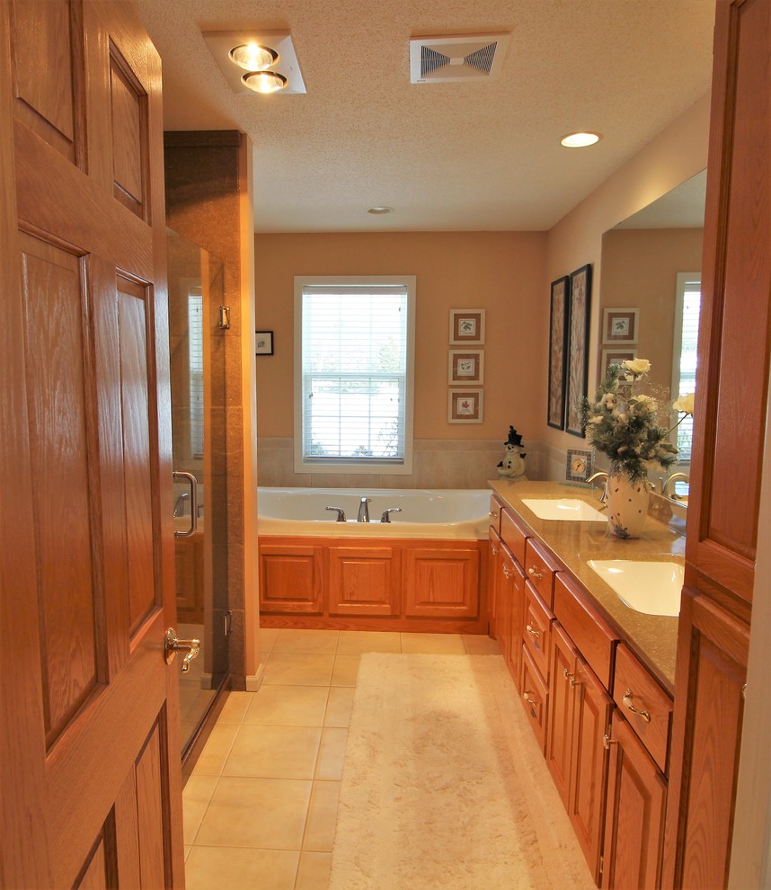 Example of a large classic master ceramic tile and beige floor bathroom design in Minneapolis with raised-panel cabinets, medium tone wood cabinets, a two-piece toilet, beige walls, an integrated sink, onyx countertops and a hinged shower door