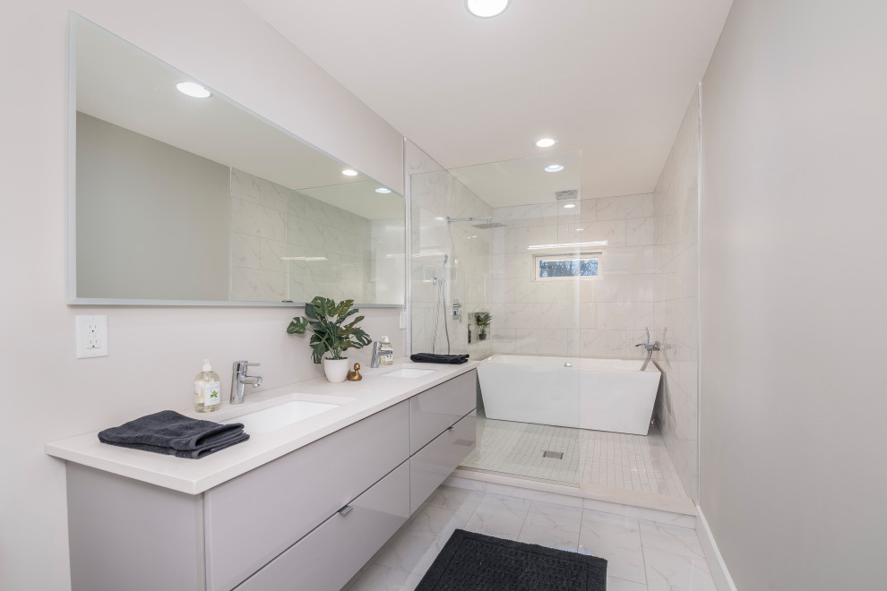 Cette photo montre une salle de bain principale chic de taille moyenne avec un placard à porte plane, des portes de placard grises, une baignoire en alcôve, un combiné douche/baignoire, un carrelage blanc, du carrelage en marbre, un mur gris, un sol en marbre, un lavabo posé, un plan de toilette en surface solide, un sol blanc, une cabine de douche à porte coulissante, un plan de toilette blanc, une niche, meuble double vasque et meuble-lavabo suspendu.