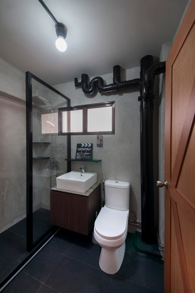 Industriell inredning av ett badrum, med släta luckor, skåp i mörkt trä, en öppen dusch, svart kakel, ett fristående handfat och med dusch som är öppen